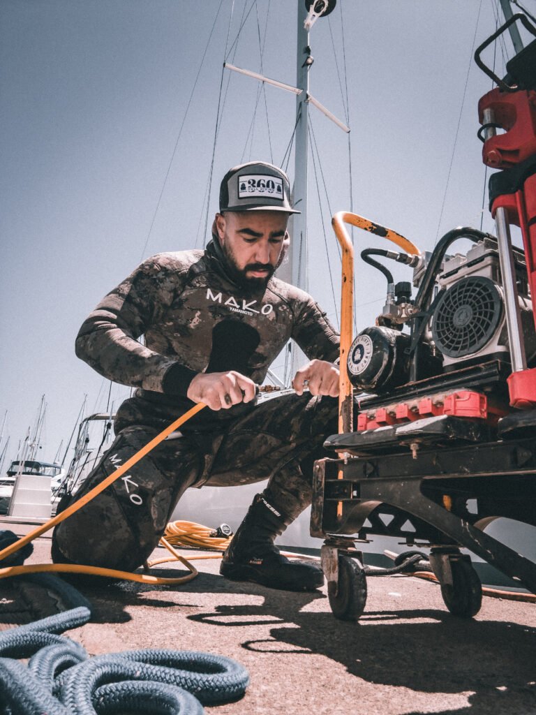 Professional diver preparing underwater hull cleaning equipment at a marina