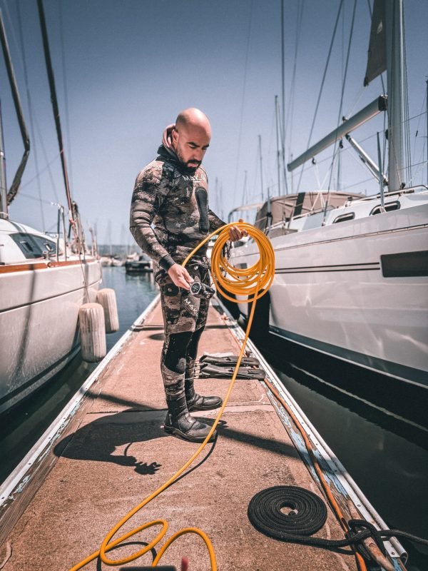 Professional diver preparing underwater hull cleaning equipment at a marina