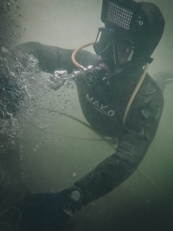 Professional diver cleaning a boat hull underwater with full diving equipment