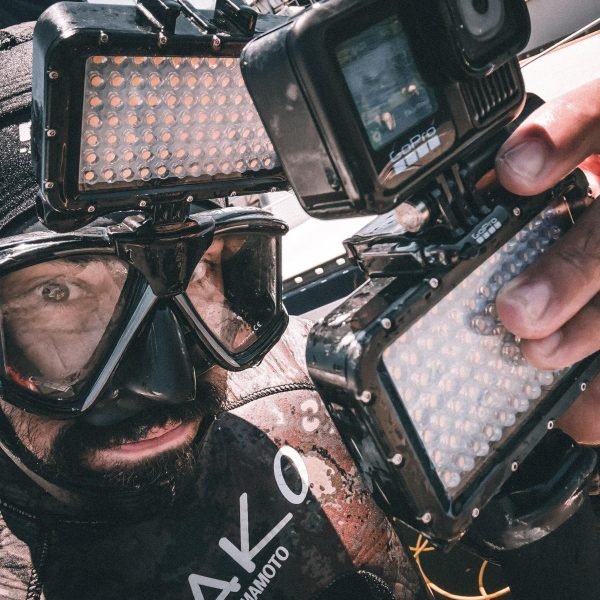 Professional commercial diver using GoPro camera and underwater lights for boat inspection